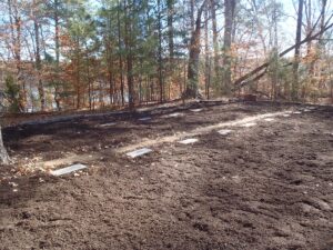 A newly cleaned up row of cemetary headstones laid flat in the ground.